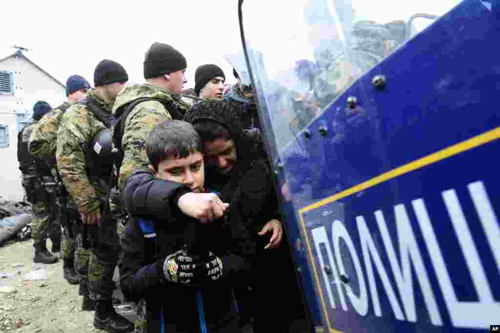 Cảnh sát Macedonia đứng gác trong khi một người phụ nữ và một đứa trẻ đi từ làng Idomeni ở miền bắc Hy Lạp tới miền nam Macedonia.
