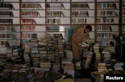 A librarian selects books that are being cataloged in the library at the Al-Nadwa Madrassa in Murree, Pakistan, Oct. 24, 2017.