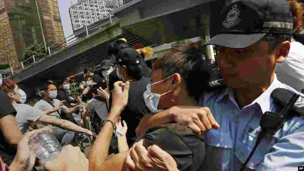 Un policier essaie de stopper un home qui démonte les barricades métalliques que des manifestants ont érigées pour bloquer la route au centre du district économique de Hong Kong, le 13 octobre 2014. (AP Photo/Vincent Yu) 