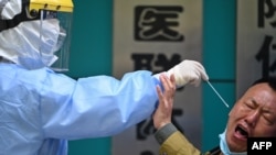 A man being tested for the COVID-19 novel coronavirus reacts as a medical worker takes a swab sample in Wuhan in China's central Hubei province on April 16, 2020.