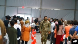 FILE - Afghan refugees line up for food in a dining hall at Fort Bliss' Doña Ana Village where they are being housed in Chaparral, N.M., Sept. 10, 2021.