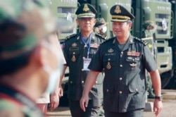 One of Cambodian Prime Minister Hun Sen's sons, Lt. Gen. Hun Manet, right, arrives for handing over ceremony at National Olympic Stadium in Phnom Penh, Cambodia, Thursday, June 18, 2020. Manet on Thursday handed over about 290 military trucks to military units throughout the country. (AP Photo/Heng Sinith)