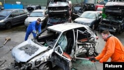 Twin brothers Steven and Brian Krijger use hammers to scrap a car to express their frustration as the Netherlands undergoes another lockdown in Vijfhuizen, Netherlands January 5, 2022. Picture taken January 5, 2022. (REUTERS/Piroschka van de Wouw)