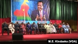 Government ministers sit under a banner depicting Cameroonian President Paul Biya during celebrations marking Biya's 86th birthday, at Yaounde Conference Center, in Yaounde, Cameroon, Feb 13, 2019.