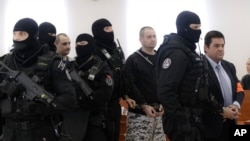 Marian Kocner the suspected mastermind in the slaying of an investigative journalist Jan Kuciak and his fiancee Martina Kusnirova , who were shot dead in their home on Feb. 21, 2018, suspected shooters Miroslav Marcek and Tomas Szabo, left, escorted by armed police officers from a courtroom after a trial session in Pezinok, Slovakia, Thursday, Dec. 19, 2019.