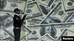 A security guard walks past a montage of old U.S. dollar bills outside a currency exchange bureau ahead of a scheduled State visit by the U.S. President Barack Obama in Kenya's capital Nairobi, July 23, 2015. 