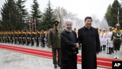 Chinese President Xi Jinping, center right, shakes hands with Iranian President Hassan Rouhani, as they pose for a photograph in an official arrival ceremony, at the Saadabad Palace in Tehran, Iran, Jan. 23, 2016. 