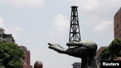 Un hombre camina junto a una escultura frente a un edificio de la compañía petrolera estatal de Venezuela PDVSA en Caracas, Venezuela. 17 de mayo de 2019. 