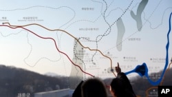 FILE - People look at a map of the border area between North and South Koreas at the Imjingak Pavilion near the border village of Panmunjom, which has separated the two Koreas since the Korean War, in Paju, north of Seoul, South Korea, Monday, Jan. 11, 2016.