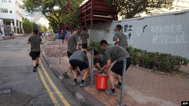 中國駐港部隊軍人星期六（11月16日）在香港清除抗議活動之後留下的路障和垃圾。