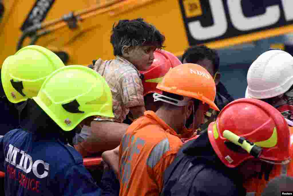 Rescue workers carry Mohammed Bangi, a four-year-old boy, after he was rescued from the remains of a collapsed five-story building in Mahad, in the western state of Maharashtra, India.