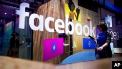 In this Tuesday, April 18, 2017, file photo, a conference worker passes a demo booth at Facebook's annual F8 developer conference in San Jose, Calif. Facebook Inc. reports earnings Wednesday, Nov. 1, 2017. (AP Photo/Noah Berger, File)