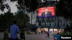 北京一家商场的电子屏幕上播放中国国家主席习近平出席全国政协年度会议开幕式。（2020年5月21日）