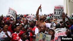 Mourners sing as they hold posters with the picture of South African national football team goalkeeper and captain Senzo Meyiwa during his funeral in Durban, Nov. 1, 2014. 