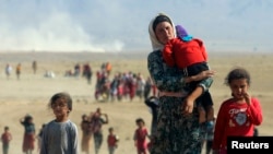 Les personnes déplacées de la secte minoritaire Yazidi, fuyant la violence des forces loyales à l'État islamique dans la ville de Sinjar, marchent vers la frontière syrienne, à la périphérie de montagne Sinjar, près de la ville frontalière syrienne d’Elierbeh, 11 août 2014. REUTERS / Rodi Said 