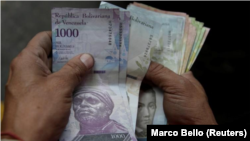 Un trabajador cuenta bolívares venezolanos en una gasolinera de la petrolera estatal PDVSA en Caracas, Venezuela, el 1 de diciembre de 2017. REUTERS / Marco Bello.