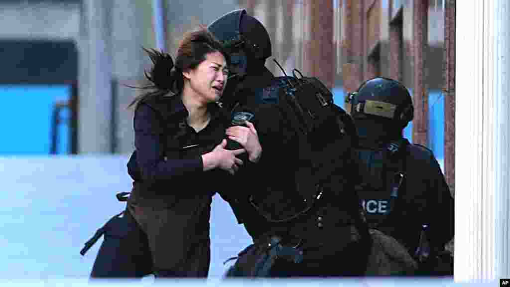 A hostage runs to armed tactical response police officers for safety after she escaped from a cafe under siege at Martin Place in the central business district of Sydney, Australia, Monday, Dec. 15, 2014.