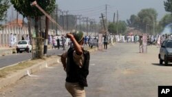 Indian paramilitary soldier aims his sling at Kashmiri protesters during during a clash between them in Srinagar, India, Aug. 9, 2013. 