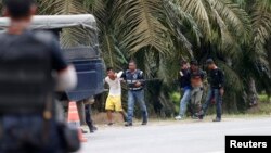 Polisi Malaysia menahan dua orang pria yang keluar dari desa Tanjung Labian, dekat daerah perkebunan di Sabah (6/3). 