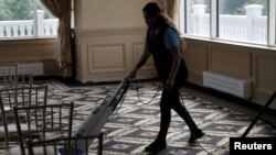 FILE - An employee vacuums the floor inside the clubhouse of the Trump National Golf Club Westchester, in Briarcliff Manor, N.Y., June 7, 2016. 
