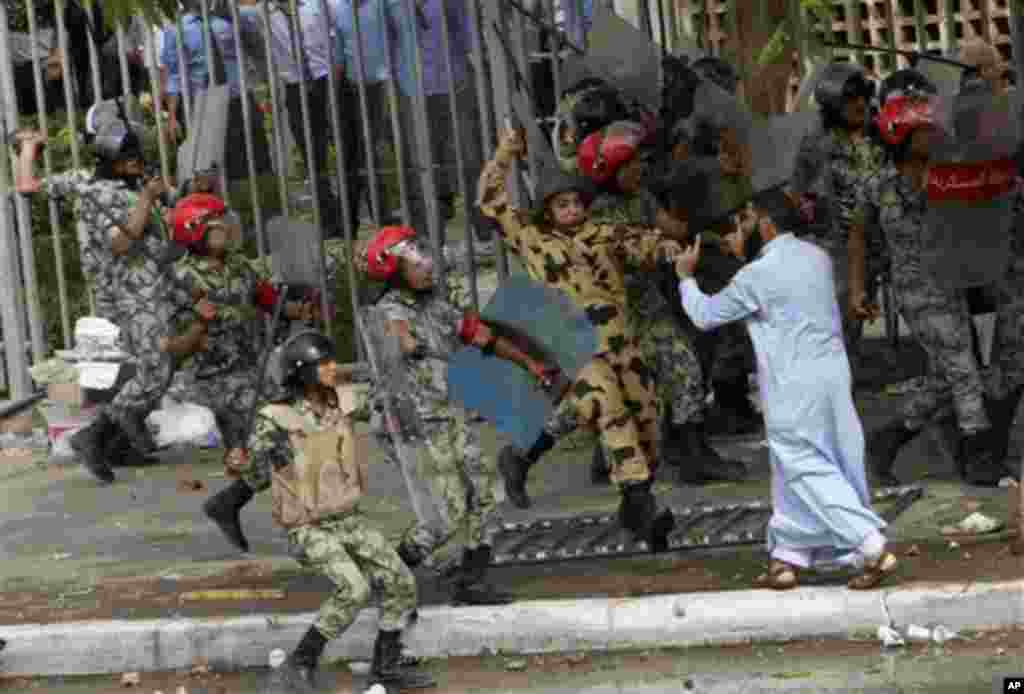 Egyptian soldiers raise their batons at a protester during clashes outside the Ministry of Defense in Cairo, Egypt, Friday, May 4, 2012. Egyptian armed forces and protesters clashed in Cairo on Friday, with troops firing water cannons and tear gas at demo