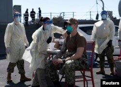 FILE - A United States Navy officer from the USS San Diego receives a vaccine against coronavirus at the navy port in Manama, Bahrain in this picture taken February 26, 2021 and released by U.S Navy on February 27, 2021. (Brandon Woods/U.S. Navy/Handout via REUTERS)