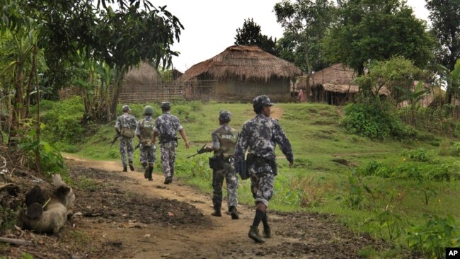 In this July 14, 2017 photo, Myanmar Border Guard Police (BGP) officers walk along a path in Tin May village, in which Myanmar government and military claim the existence of Muslim terrorists in Rakhine State, Myanmar.