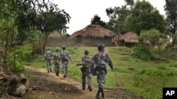 In this July 14, 2017 photo, Myanmar Border Guard Police (BGP) officers walk along a path in Tin May village, in which Myanmar government and military claim the existence of Muslim terrorists in Rakhine State, Myanmar.