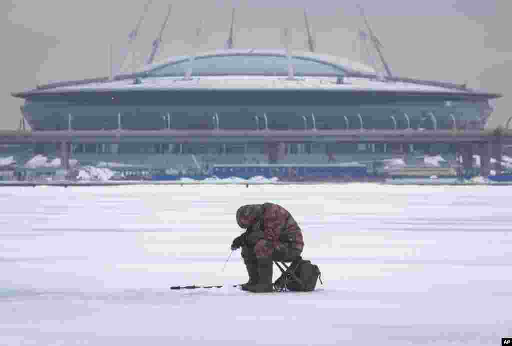 A man fishes through an ice hole in the Finnish Gulf in St. Petersburg, Russia.