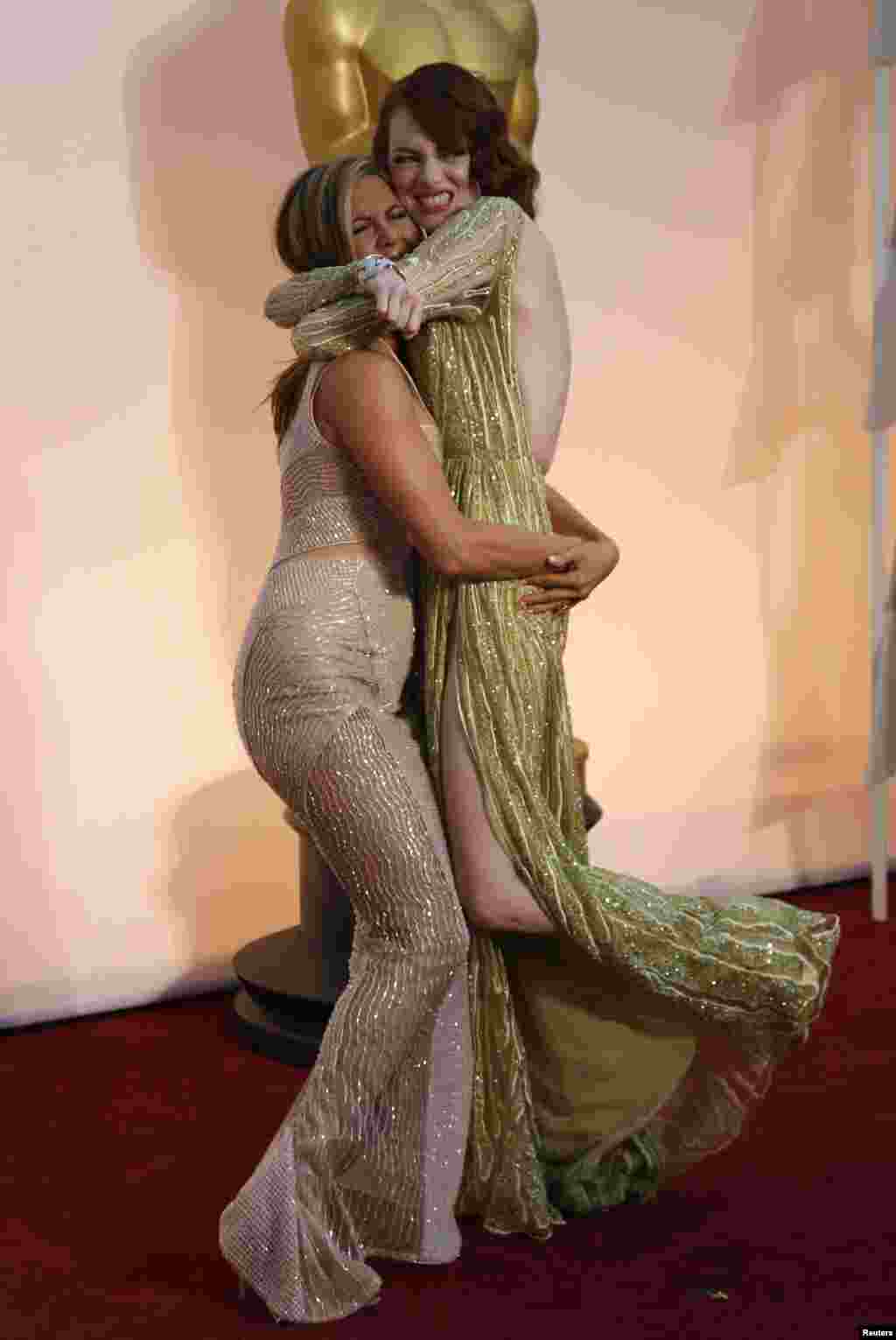A actriz Jennifer Aniston eleva a colega Emma Stone num grande abraço em plena passadeira vermelha à chegada aos Oscars