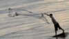 FILE - A man casts a fishing net on the bank of the Mekong river in Phnom Penh. 