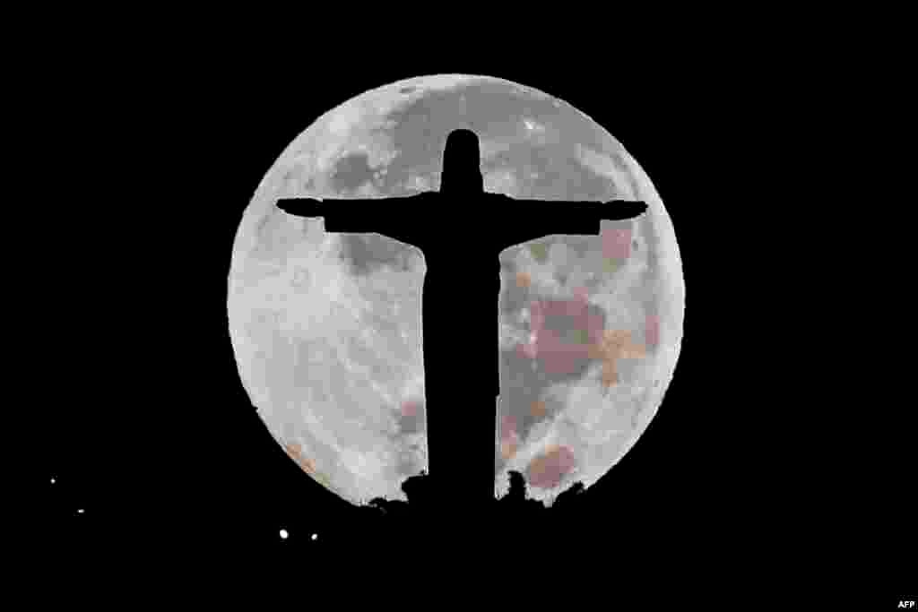 The Cristo Rey monument is silhouetted against the full moon in Cali, Colombia.