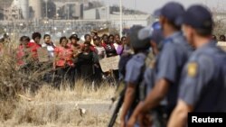 Police look on as women protest against the killing of miners by South African police on Thursday, outside a South African mine in Rustenburg, August 17, 2012.