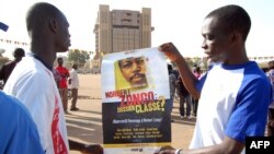 FILE - Demonstrators hold a poster with a portrait of late journalist Norbert Zongo during a protest in Ouagadougo.