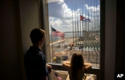 Children look out a window from inside the newly opened U.S. Embassy, at the end of a flag-raising ceremony, in Havana, Cuba, Aug. 14, 2015.