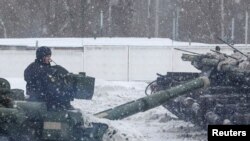 A service member drives a tank during snowfall as a mechanized brigade of the Ukrainian Armed Forces holds drills outside Kharkiv, Ukraine, Jan. 31, 2022. 