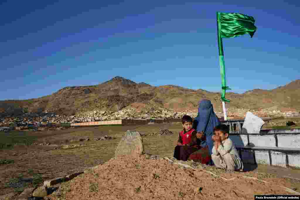 نسیمه ای ۲۷ ساله با دوفرزند خود در حال دعا بر سر قبر شوهر اش در کابل. مسعود، شوهر نسیمه سرباز اردوی ملی افغانستان بود و در یک انقجار بم کنار جاده در ولایت لوگر کشته شد. نسیمه در سن ۱۶ سالگی ازدواج کرده و چهار فرزند دارد. او بیکار است و زندگی را با کمک مالی اقارب خود به پیش می برد.