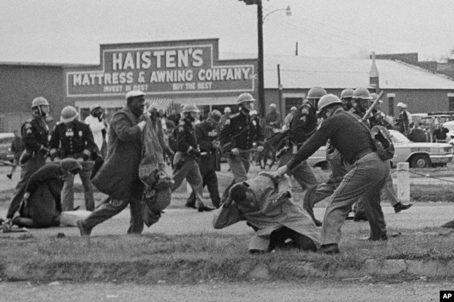 FILE - State troopers swing billy clubs to break up a civil rights voting march in Selma, Ala., March 7, 1965. John Lewis, chairman of the Student Nonviolent Coordinating Committee (in the foreground) is being beaten by a state trooper. (AP Photo)