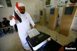 An Iraqi man casts his vote electronically at a polling station during the parliamentary election in Baghdad, May 12, 2018.