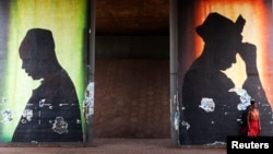A woman stands in front of a poster in Bamako, Mali, Feb. 21, 2014.