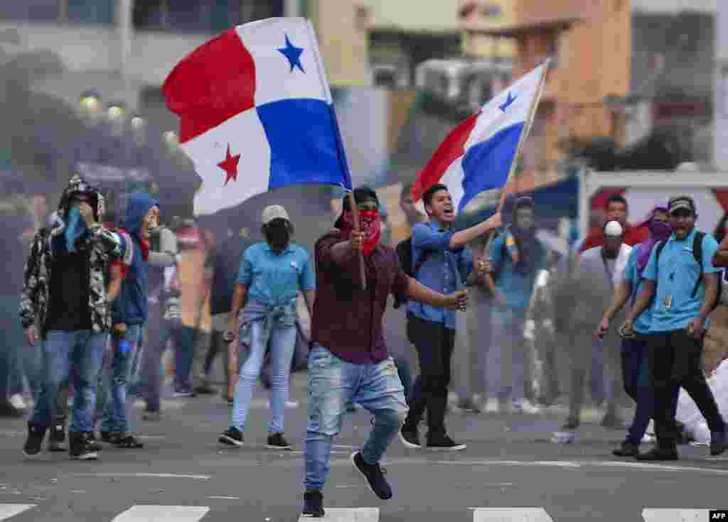 Los manifestantes agitan banderas durante los enfrentamientos con la policía antidisturbios durante una protesta de estudiantes, miembros de organizaciones de la sociedad civil y sindicatos. 