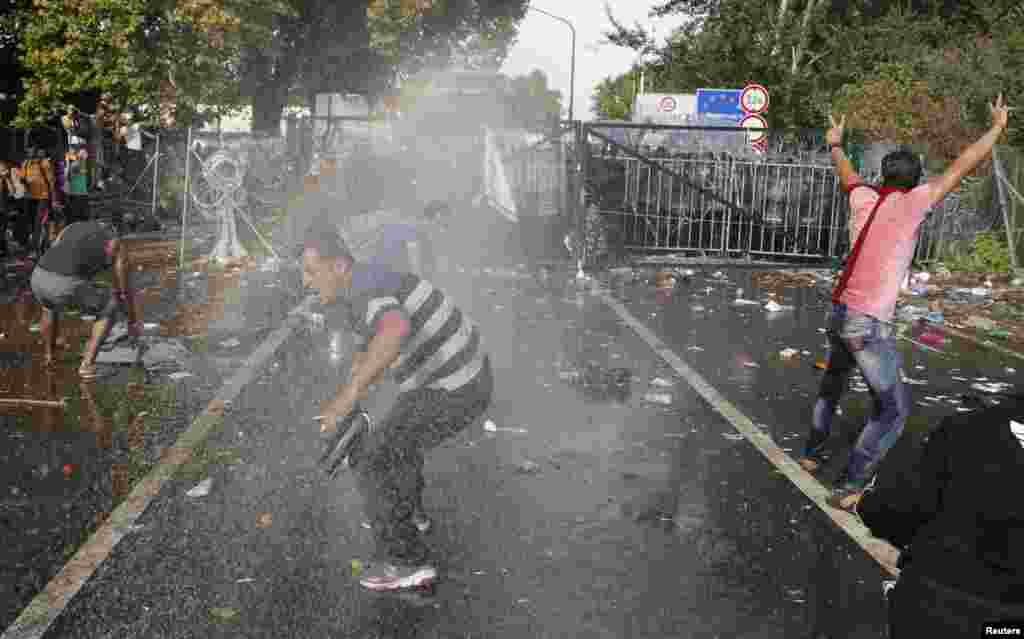 Migrants react on the Serbian side of the border as Hungarian riot police fires tear gas and water cannon near Roszke, Sept.16, 2015. Police fired tear gas and water cannon at protesting migrants demanding they be allowed to enter from Serbia on Wednesday on the second day of a border crackdown.