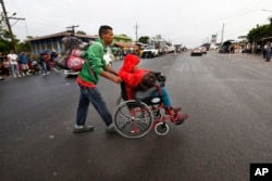 Nicaraguan migrant Javier Velazquez wheels his 14-year-old son across a highway, as part of the Central American migrant caravan hoping to reach the U.S. border, in Acayucan, Veracruz state, Mexico, Nov. 3, 2018. Javier Velazquez said that Axel was shot in the leg during protests in Nicaragua and both are looking for political asylum in the United States.