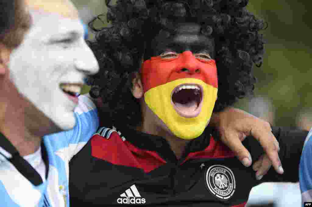 An Argentina and Germany fan with their faces painted in the national colors cheer before the 2014 FIFA World Cup final football match between Germany and Argentina at Maracana Stadium in Rio de Janeiro, Brazil.