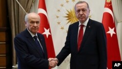 Devlet Bahceli, left, leader of Nationalist Movement Party, or MHP, and the main ally of Turkey's President Recep Tayyip Erdogan, right, shake hands before a meeting at the presidential palace in Ankara, Turkey, June 27, 2018.