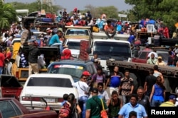 FILE - Venezuelans line up to cross into Colombia at the border in Paraguachon, Colombia, Feb. 16, 2018.