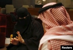 FILE - A Saudi woman gestures to her chaperones at a shopping mall in Riyadh, Saudi Arabia, Nov. 29, 2015.