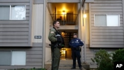 Douglas County Deputy Sheriff Greg Kennerly, left, and Oregon State Trooper Tom Willis, stand guard outside the apartment building, Oct. 2 2015, where alleged Umpqua Community College gunman Chris Harper Mercer lived, in Roseburg, Ore. (AP Photo/Rich Pedroncelli)