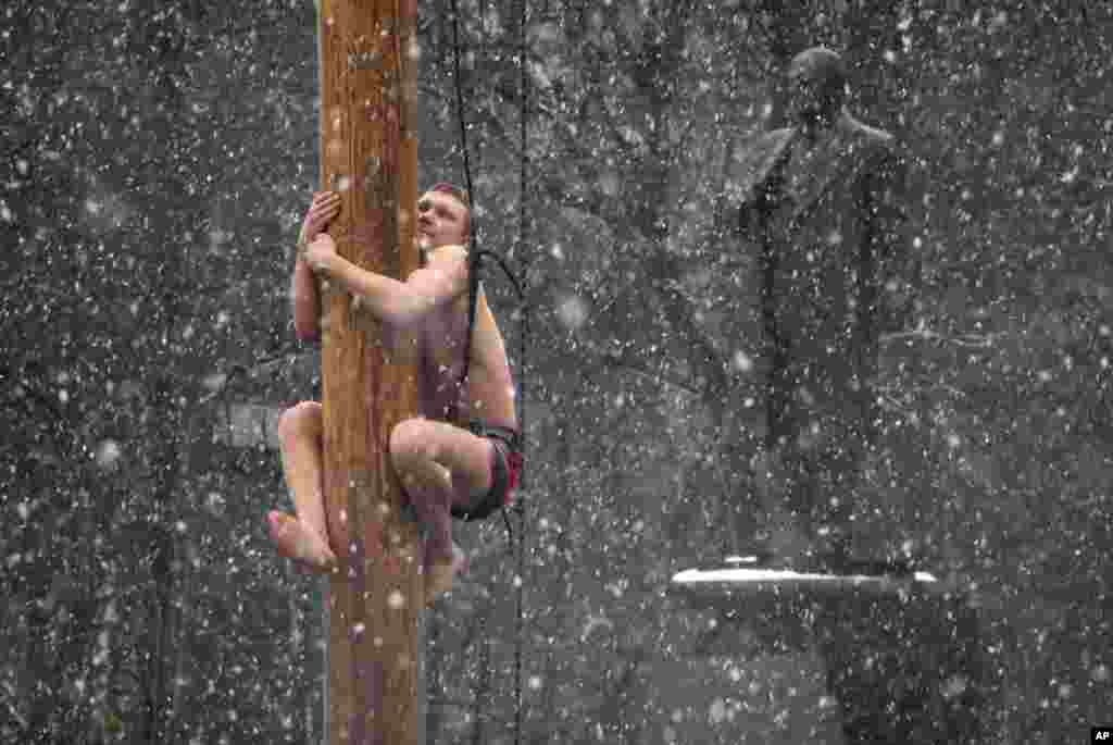 A man climbs on a pole in snowfall to get a prize during celebrations of Maslenitsa, or Pancake Week, in Veliky Novgorod, some 550 kilometers (340 miles) northeast of Moscow, Russia.