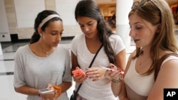  Isabella Cimato, 17, left, Arianna Schaden, 14, center, and Sofia Harrison, 15, check their phones at Roosevelt Field shopping mall in Garden City, N.Y. 